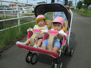 保育園の子供達が二人乗りの散歩車に乗っている様子