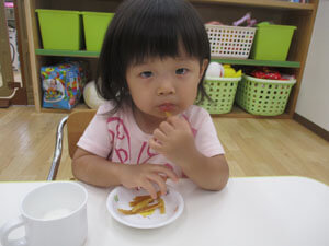 保育園の子どもがおやつの芋けんぴを食べる様子