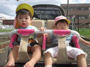 保育園の子供達が二人乗りの散歩車に乗っている様子
