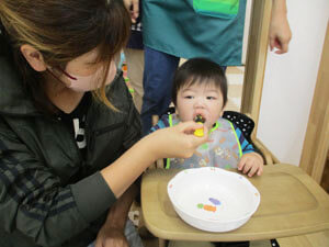 保育園で食事をする親子の写真
