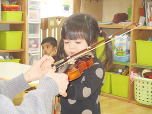 保育園でバイオリンを弾く園児写真