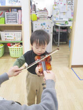 保育園でバイオリンを弾く園児写真