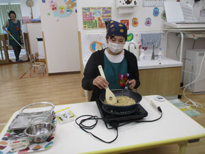 保育園で大豆をいる先生