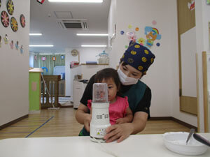 ミキサーでちりめんじゃこを細かくする先生と園児