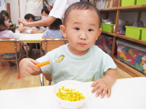 とうもろこしの料理を食べる保育園児