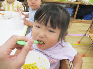とうもろこしの料理を食べる保育園児