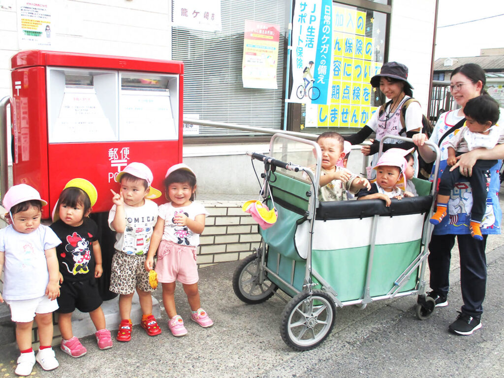 郵便局の前で保育園児が先生と集合している様子