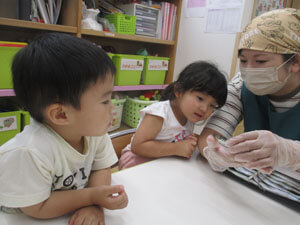 ししゃもを見せる保育園の先生と園児たち