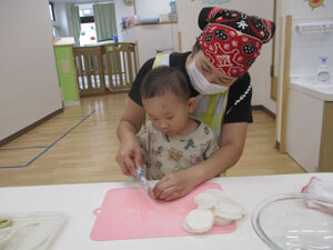 先生と大根を切る保育園児