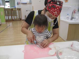 先生と大根を切る保育園児