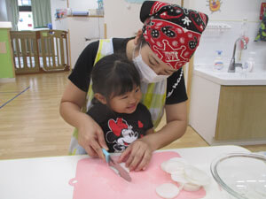 先生と大根を切る保育園児