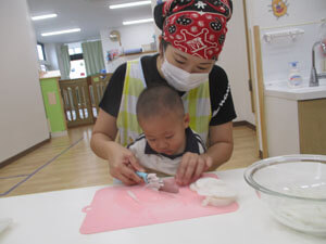 先生と大根を切る保育園児