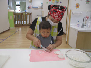 先生と大根を切る保育園児