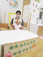 誕生日会の様子、先生に抱っこをされる保育園児