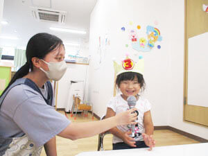 保育園での誕生日会の様子、インタビューする先生と笑顔の保育園児