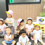 手作りお月見団子とススキの前で集合写真を撮る保育園児