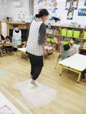 小麦粉を踏んでうどんを作る保育園の先生の様子