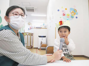 誕生日会でインタビューをする先生とインタビューを受ける保育園児の様子