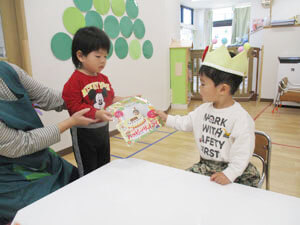 誕生日会でプレゼントを受け取る保育園児とプレゼントを渡す保育園児の様子