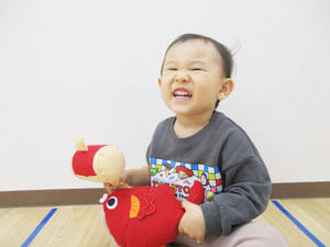 鯛のぬいぐるみを持つ笑顔の保育園児