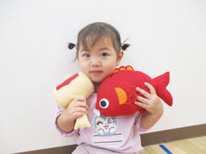 鯛のぬいぐるみを持つ笑顔の保育園児