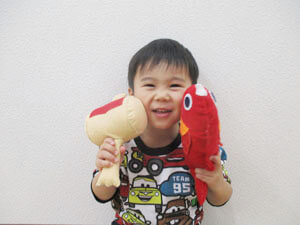 鯛のぬいぐるみを持つ笑顔の保育園児