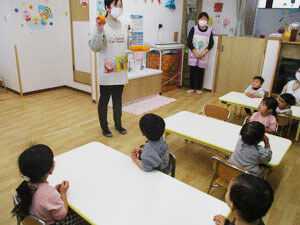 保育園で先生が園児達の前で話す様子