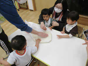 うどんの生地を触る保育園児と先生