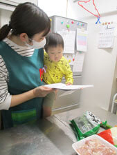 給食室で給食の先生に抱っこされる園児の様子