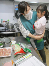 給食室で給食の先生に抱っこされる園児の様子