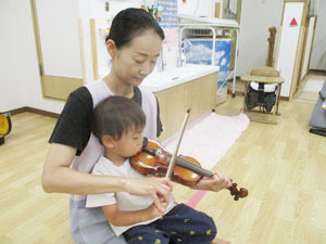 先生にバイオリンを教えてもらう保育園児