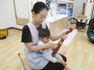 先生にバイオリンを教えてもらう保育園児