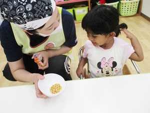 保育園児が先生が持つコーンを覗き込む様子