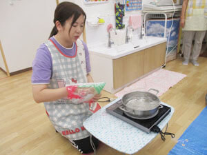 保育園の先生が園児の前で春雨を茹でる様子