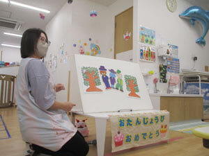 保育園の誕生日会で先生がパネルシアターを行う様子。