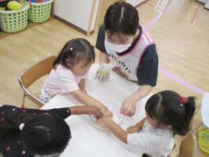 保育園の先生とお月見団子を作る保育園児の様子