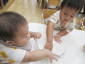 保育園の先生とお月見団子を作る保育園児の様子